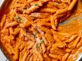 Penne alla vodka w kremowym, pomarańczowym sosie, posypane parmezanem i bazylią.