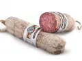 Dwie podłużne kiełbasy, jedna przekrojona, ukazująca różowe mięso i tłuszcz. Z czego jest salami? Z wieprzowiny i wołowiny, przyprawione.