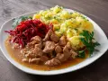 Pyszny gulasz z łopatki w sosie, podany z purée ziemniaczanym i surówką z buraczków.