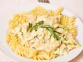 Makaron fusilli z kurczakiem w kremowym sosie, ozdobiony rozmarynem.