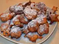 Puszyste paczki z serka homo, posypane cukrem pudrem, kuszą swoim złotym kolorem i apetycznym wyglądem.