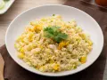 Pyszny ryż z jajkiem, posypany szczypiorkiem i pieprzem, ozdobiony gałązką kolendry. Idealny na szybki posiłek.