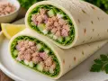 Pyszna tortilla z tuńczykiem, chrupiącym ogórkiem, czerwoną cebulą i świeżą sałatą. Idealna na szybki lunch.