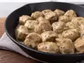 Pyszne pulpety w sosie śmietanowym, posypane ziołami, podane w żeliwnej patelni.