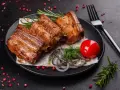 Soczyste, pieczone żeberka w rękawie, podane z pomidorkiem, cebulą i rozmarynem.