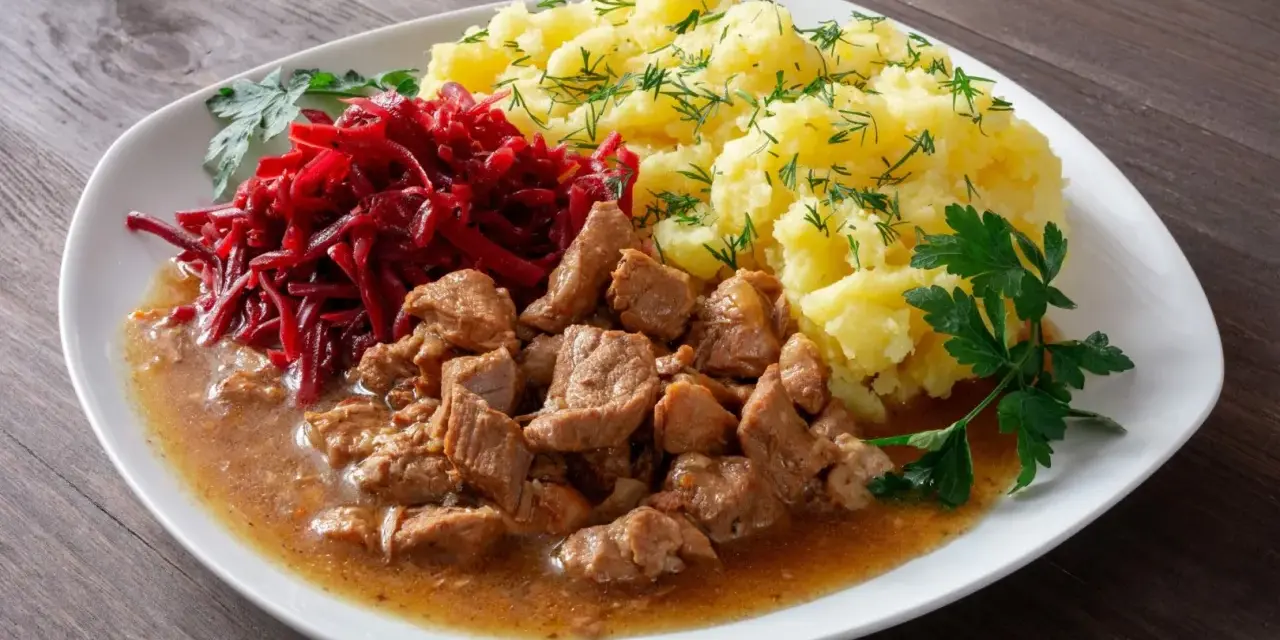 Pyszny gulasz z łopatki w sosie, podany z purée ziemniaczanym i surówką z buraczków.