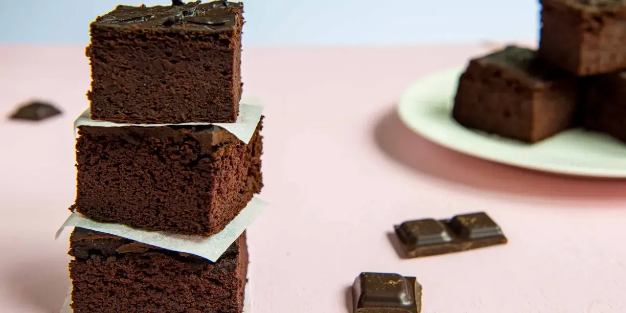 Ciemne, wilgotne brownie z fasoli, ułożone w wieżę, obok kawałków czekolady.
