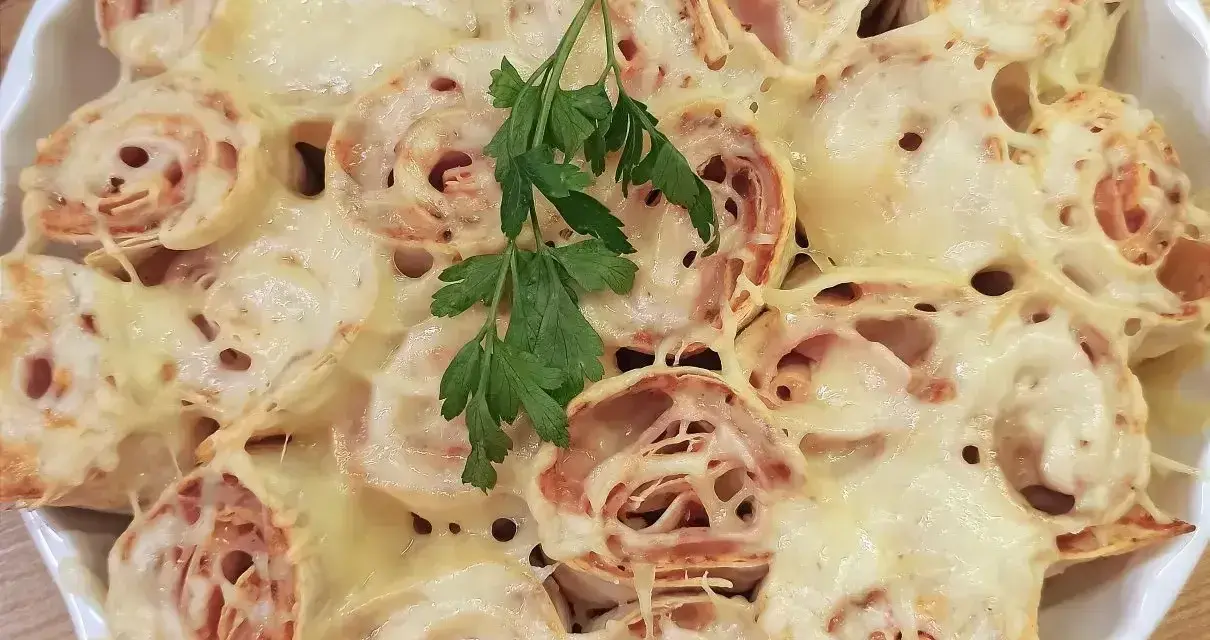 Zapiekana tortilla z szynką i ciągnącym się serem, udekorowana gałązką natki pietruszki. Pyszne danie gotowe do podania.