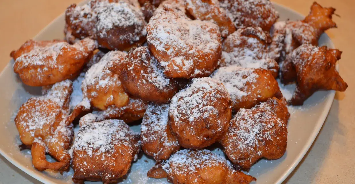 Puszyste paczki z serka homo, posypane cukrem pudrem, kuszą swoim złotym kolorem i apetycznym wyglądem.