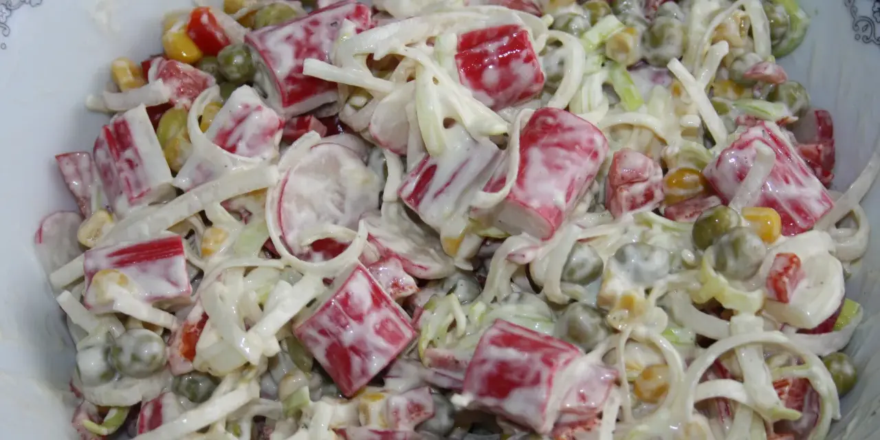 Pyszna sałatka z surimi, groszkiem, kukurydzą i porem, polana kremowym sosem.