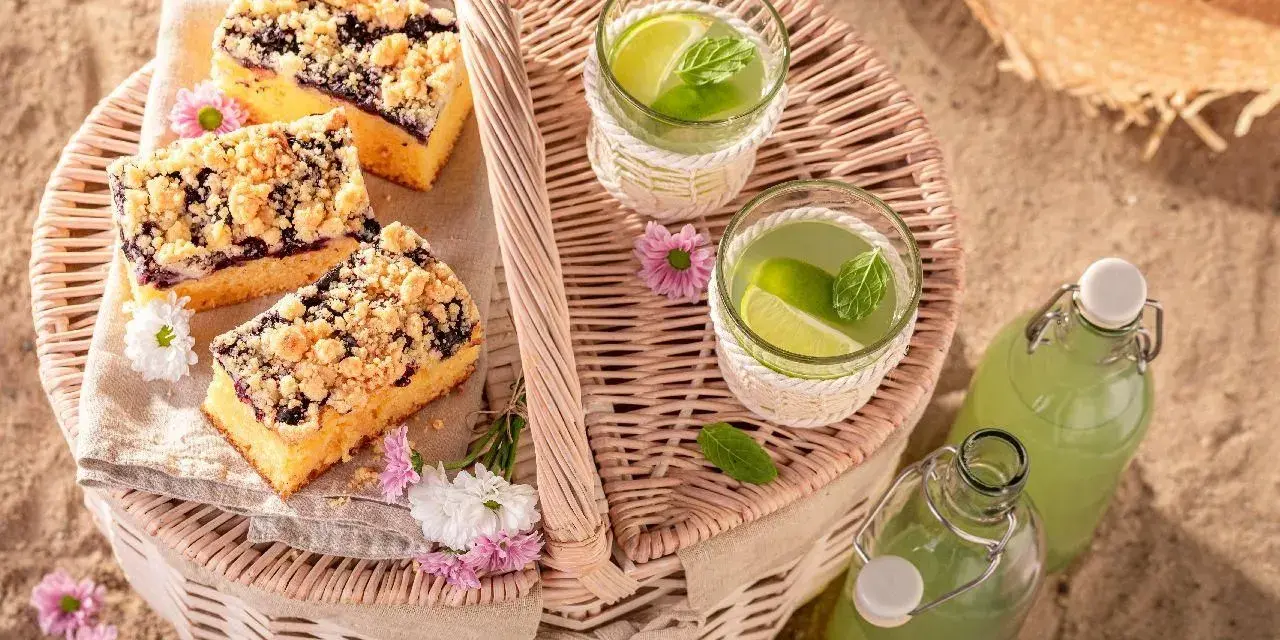 Idealne co na piknik: ciasto z jagodami, orzeźwiająca lemoniada i słomkowy kapelusz na plaży.