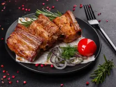 Soczyste, pieczone żeberka w rękawie, podane z pomidorkiem, cebulą i rozmarynem.