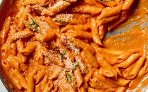 Penne alla vodka w kremowym, pomarańczowym sosie, posypane parmezanem i bazylią.