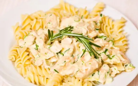 Makaron fusilli z kurczakiem w kremowym sosie, ozdobiony rozmarynem.
