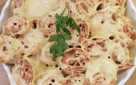Zapiekana tortilla z szynką i ciągnącym się serem, udekorowana gałązką natki pietruszki. Pyszne danie gotowe do podania.