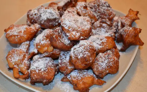 Puszyste paczki z serka homo, posypane cukrem pudrem, kuszą swoim złotym kolorem i apetycznym wyglądem.