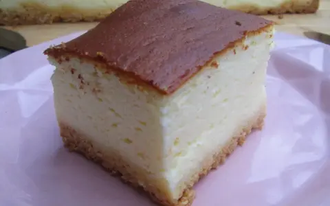 Pyszny sernik z wiaderka na różowym talerzu, z chrupiącym spodem i kremowym nadzieniem.