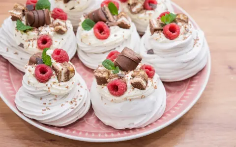 Mini bezy Pavlova z malinami i czekoladą, udekorowane listkami mięty. Idealne na deser.