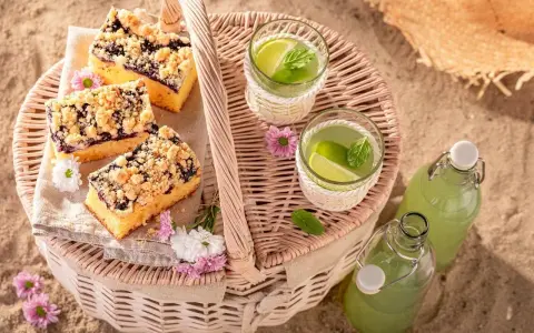 Idealne co na piknik: ciasto z jagodami, orzeźwiająca lemoniada i słomkowy kapelusz na plaży.