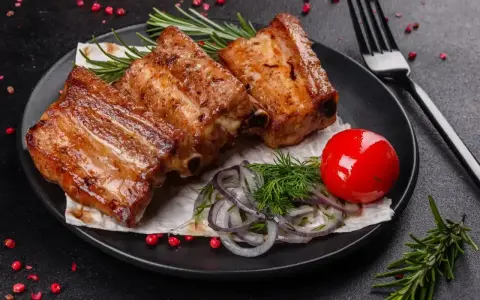 Soczyste, pieczone żeberka w rękawie, podane z pomidorkiem, cebulą i rozmarynem.
