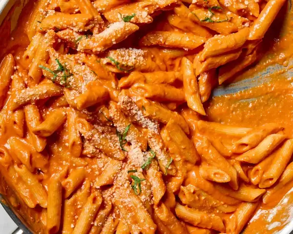 Penne alla vodka w kremowym, pomarańczowym sosie, posypane parmezanem i bazylią.