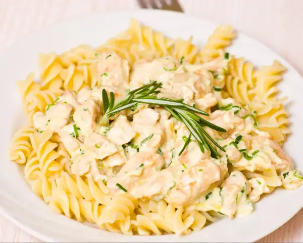 Makaron fusilli z kurczakiem w kremowym sosie, ozdobiony rozmarynem.