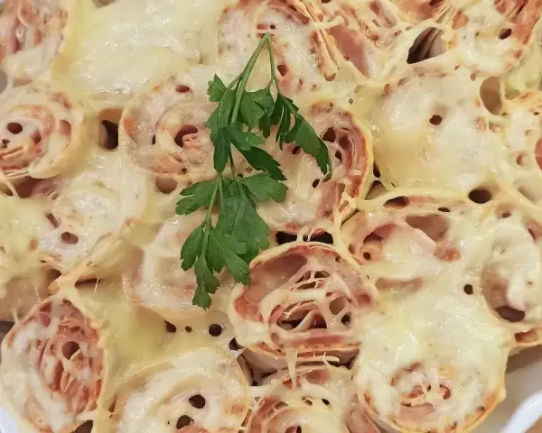 Zapiekana tortilla z szynką i ciągnącym się serem, udekorowana gałązką natki pietruszki. Pyszne danie gotowe do podania.