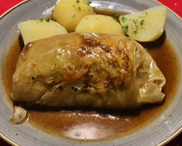 Pyszne gołąbki z kaszą gryczaną w sosie, podane z ziemniakami.
