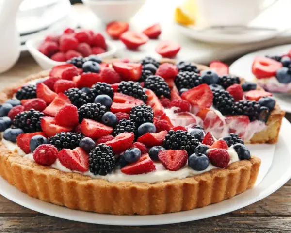 Pyszna tarta z mascarpone, obficie udekorowana świeżymi malinami, jeżynami, borówkami i truskawkami. Idealna na letnie popołudnie.