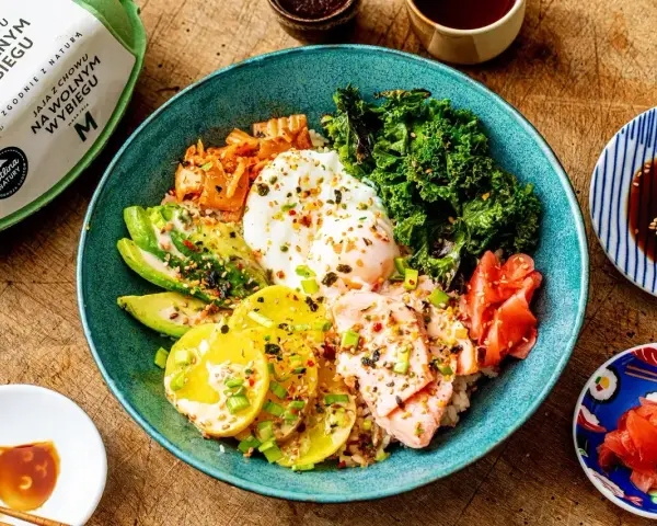 Kolorowy bowl z ryżem, łososiem, awokado, jajkiem sadzonym, jarmużem i kimchi. Pyszny bowl z lososiem na zdrowy obiad.