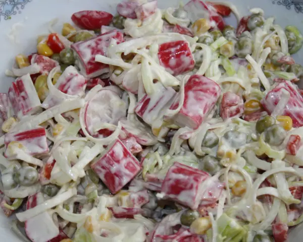 Pyszna sałatka z surimi, groszkiem, kukurydzą i porem, polana kremowym sosem.