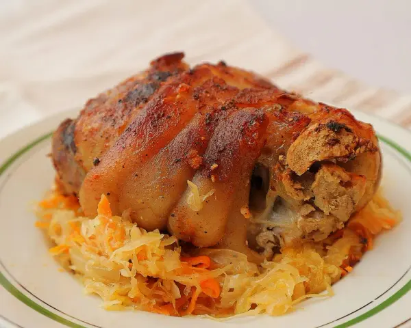 Soczysta golonka w kapuście kiszonej, pieczona do perfekcji, z chrupiącą skórką. Idealny polski obiad.
