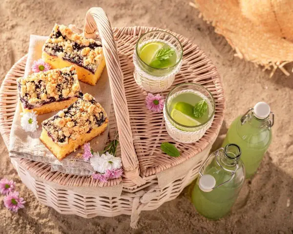 Idealne co na piknik: ciasto z jagodami, orzeźwiająca lemoniada i słomkowy kapelusz na plaży.