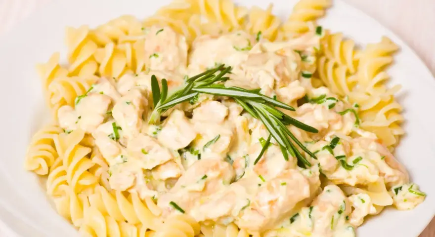 Makaron fusilli z kurczakiem w kremowym sosie, ozdobiony rozmarynem.