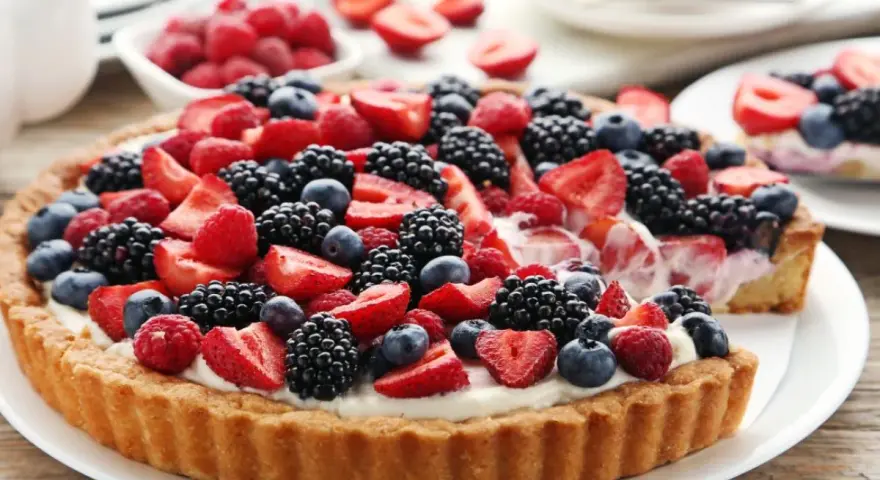 Pyszna tarta z mascarpone, obficie udekorowana świeżymi malinami, jeżynami, borówkami i truskawkami. Idealna na letnie popołudnie.