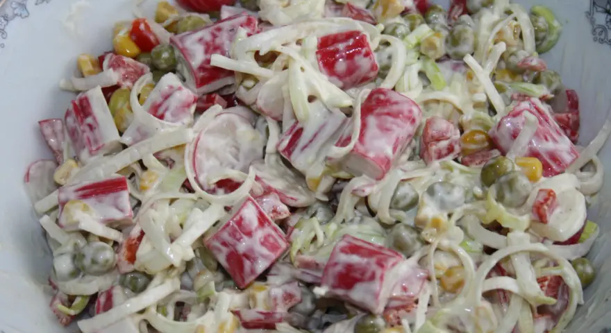 Pyszna sałatka z surimi, groszkiem, kukurydzą i porem, polana kremowym sosem.