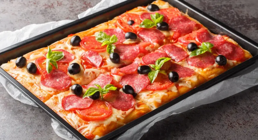 Chrupiąca pizza z ciasta francuskiego z salami, pomidorami, oliwkami i bazylią, prosto z blachy.