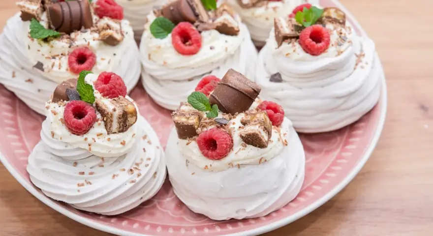 Mini bezy Pavlova z malinami i czekoladą, udekorowane listkami mięty. Idealne na deser.