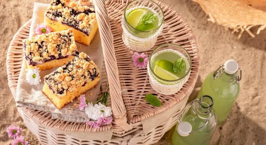 Idealne co na piknik: ciasto z jagodami, orzeźwiająca lemoniada i słomkowy kapelusz na plaży.