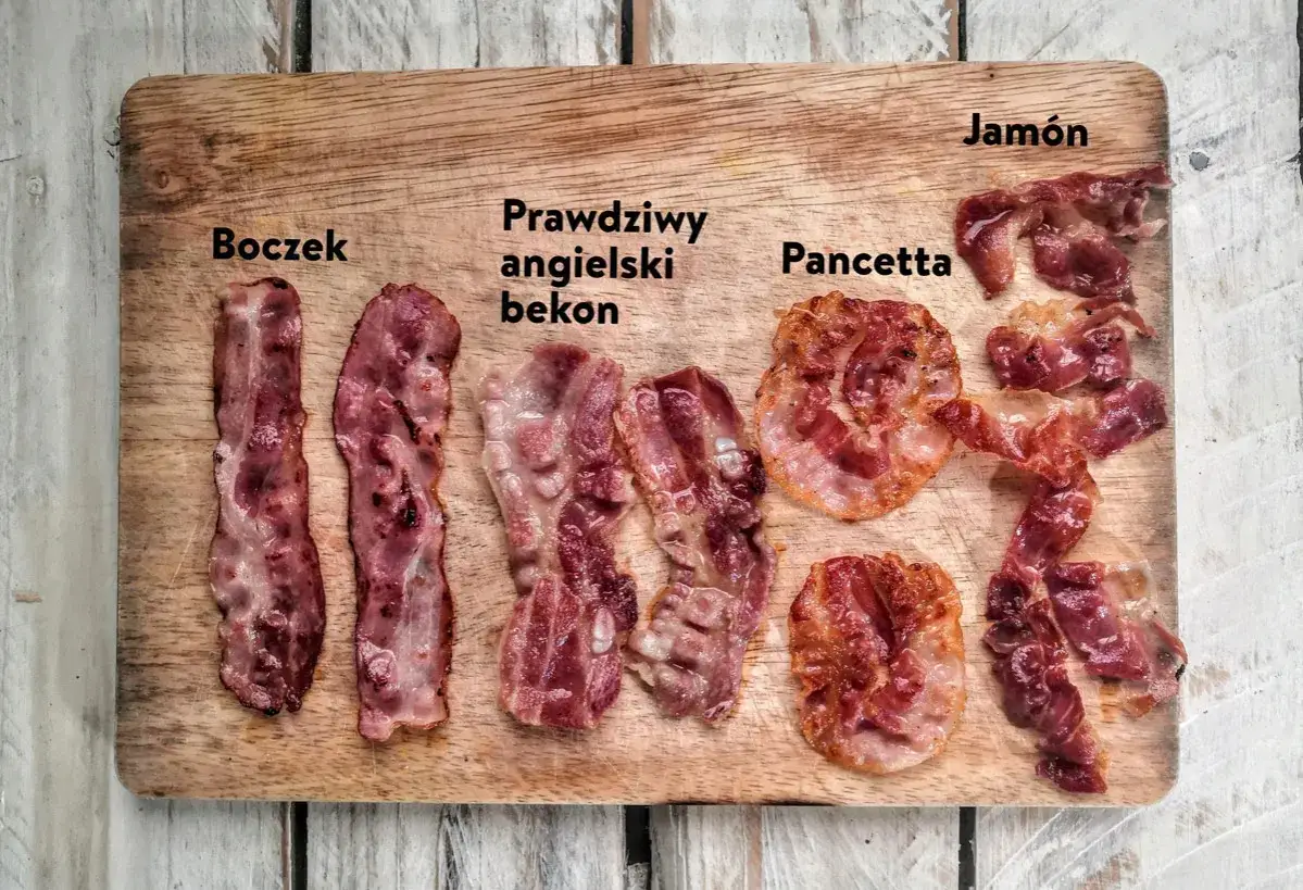 R&oacute;żne rodzaje bekonu i boczku: boczek, prawdziwy angielski bekon, pancetta i jam&oacute;n na drewnianej desce.