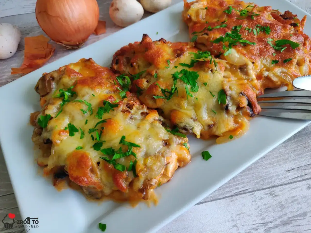 Pyszny schab w sosie pieczarkowym, zapieczony z serem i posypany natką pietruszki. Idealny obiad!