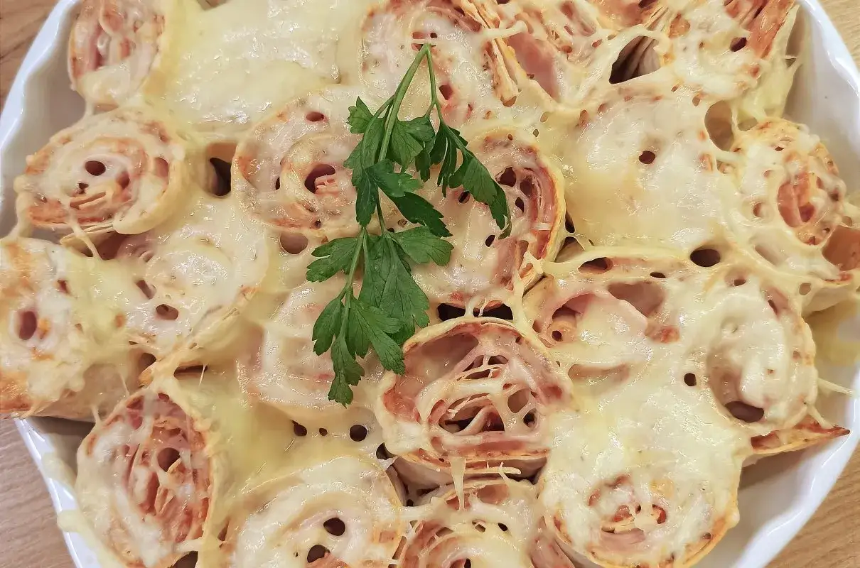 Zapiekana tortilla z szynką i serem, udekorowana natką pietruszki. Pyszne danie, kt&oacute;re zachwyci każdego.
