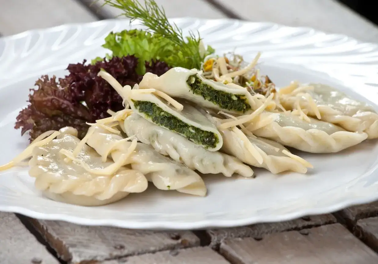 Pyszne pierogi ze szpinakiem, podane z sałatką i startym serem. Idealne na obiad!