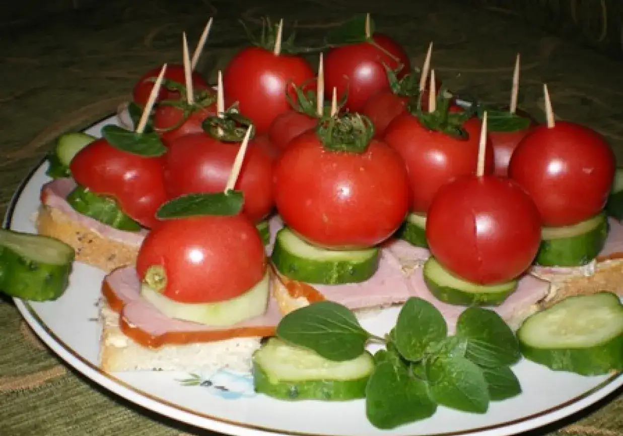 Idealne na piknik! Mini kanapki z pomidorkami, ogórkiem i szynką, ozdobione listkami ziół.