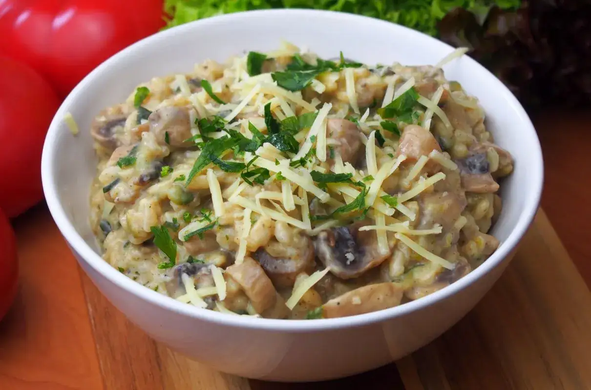 Kremowe risotto z cukinią i pieczarkami, posypane startym parmezanem i świeżą natką pietruszki.