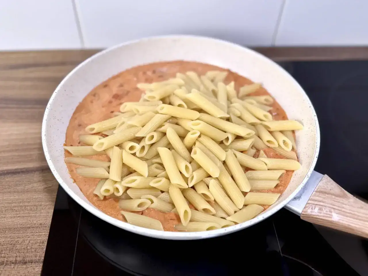 Penne w kremowym sosie pomidorowym z kawałkami chorizo, gotowe do podania.