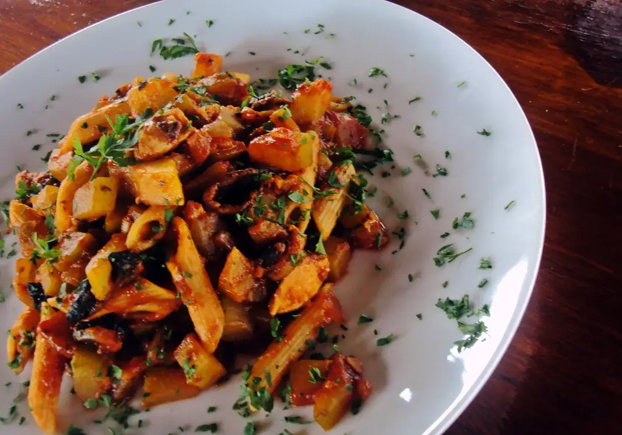 Penne z cukinią i kurczakiem w sosie pomidorowym, posypane natką pietruszki. Pyszne danie na obiad.