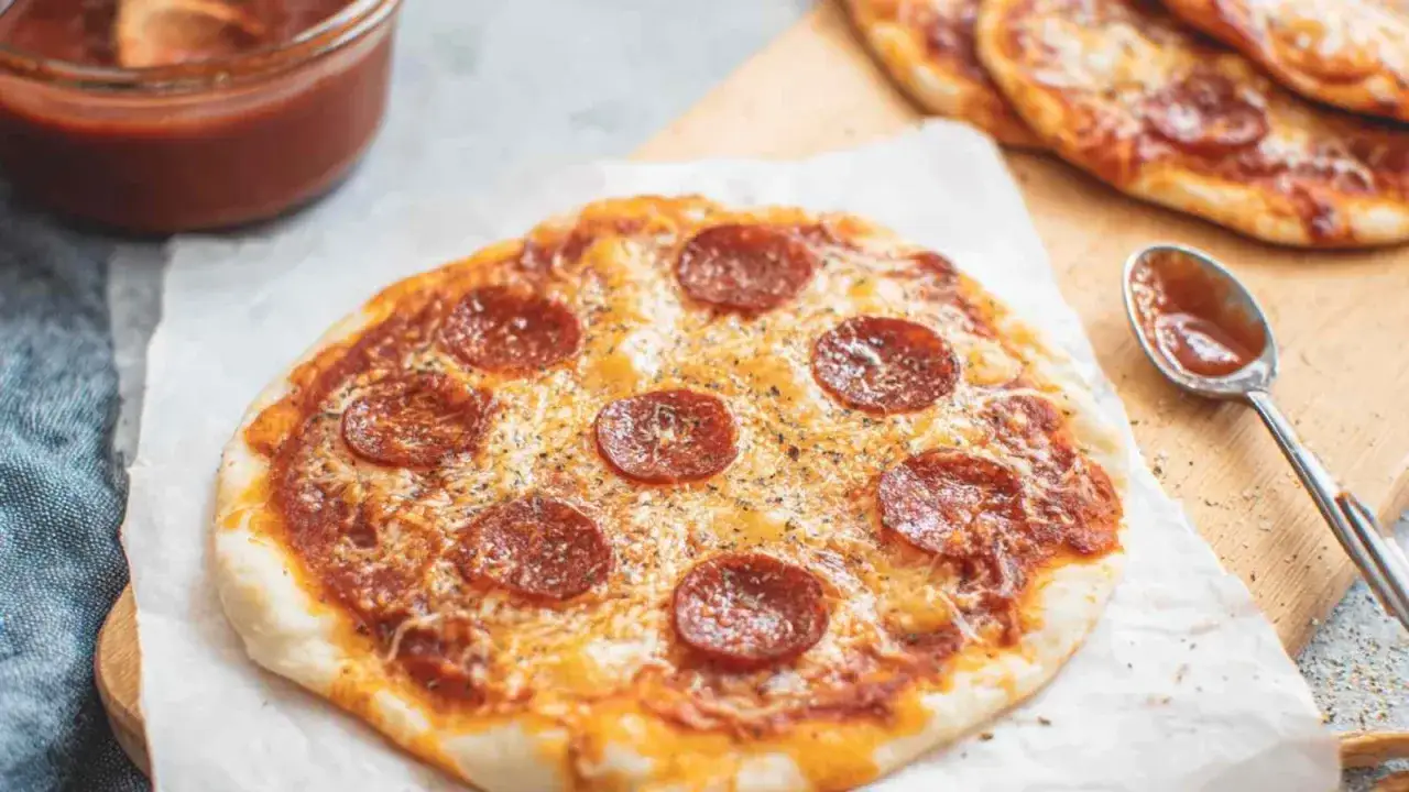Pyszna pizza z tortilli z pepperoni i serem, obok sos w miseczce i łyżeczka.