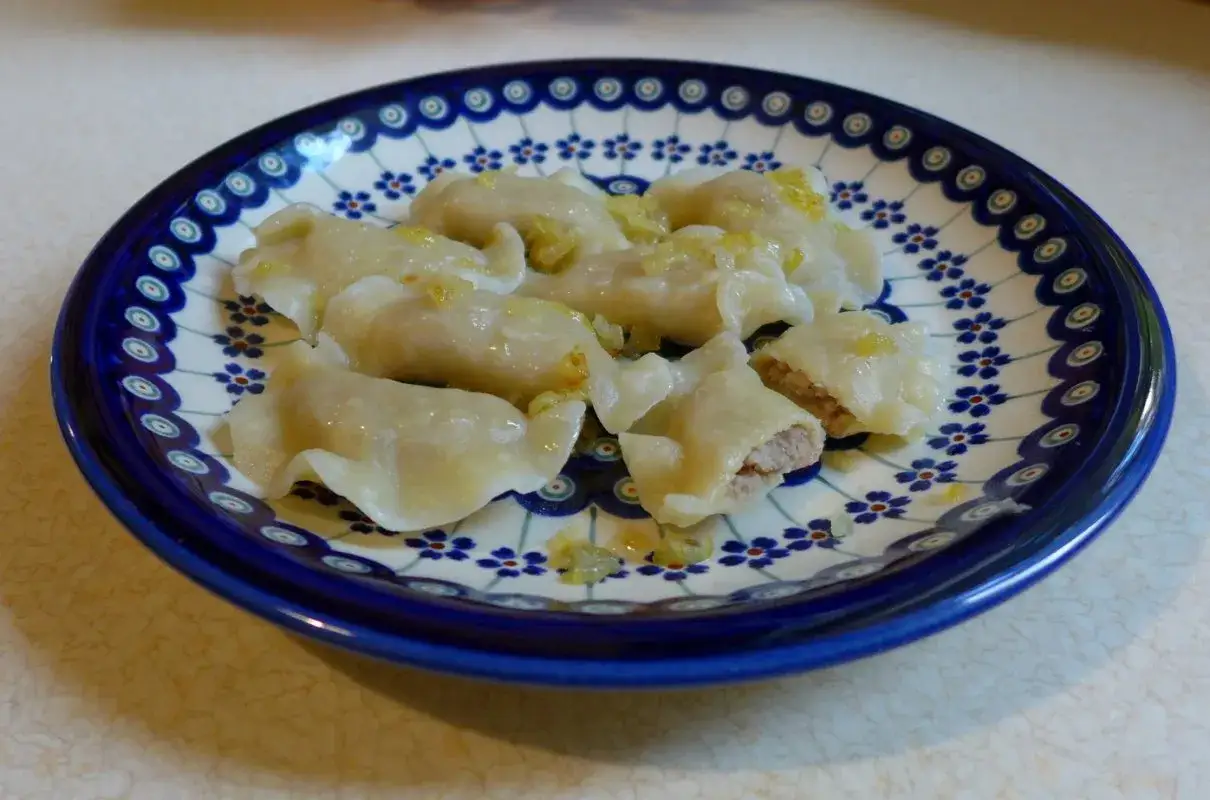 Pyszne pierogi z mięsem, ułożone na talerzu z tradycyjnym wzorem.